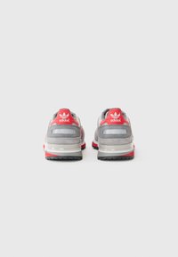 Grijze en rode sneakers met een gelaagd ontwerp, gemaakt van suede en mesh materialen, met een gevoerde kraag en rubberen zolen met grippatronen.