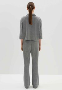 Grijze en zwarte gebreide top met patroon en kraag, gecombineerd met bijpassende wijde broek, beide met een gestructureerde, gezellige stof.