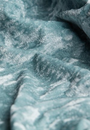 Soft, textured fabric in a muted teal color with a slight sheen and subtle wave patterns, creating a luxurious appearance.