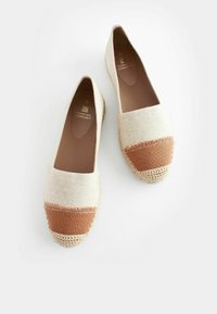 Beige kankaalin espadrilijat, hvor en brun stoffbånd og frynser detalj på tåen. Vevet sisal bunn. Merkevarelogo preget på innersålen.