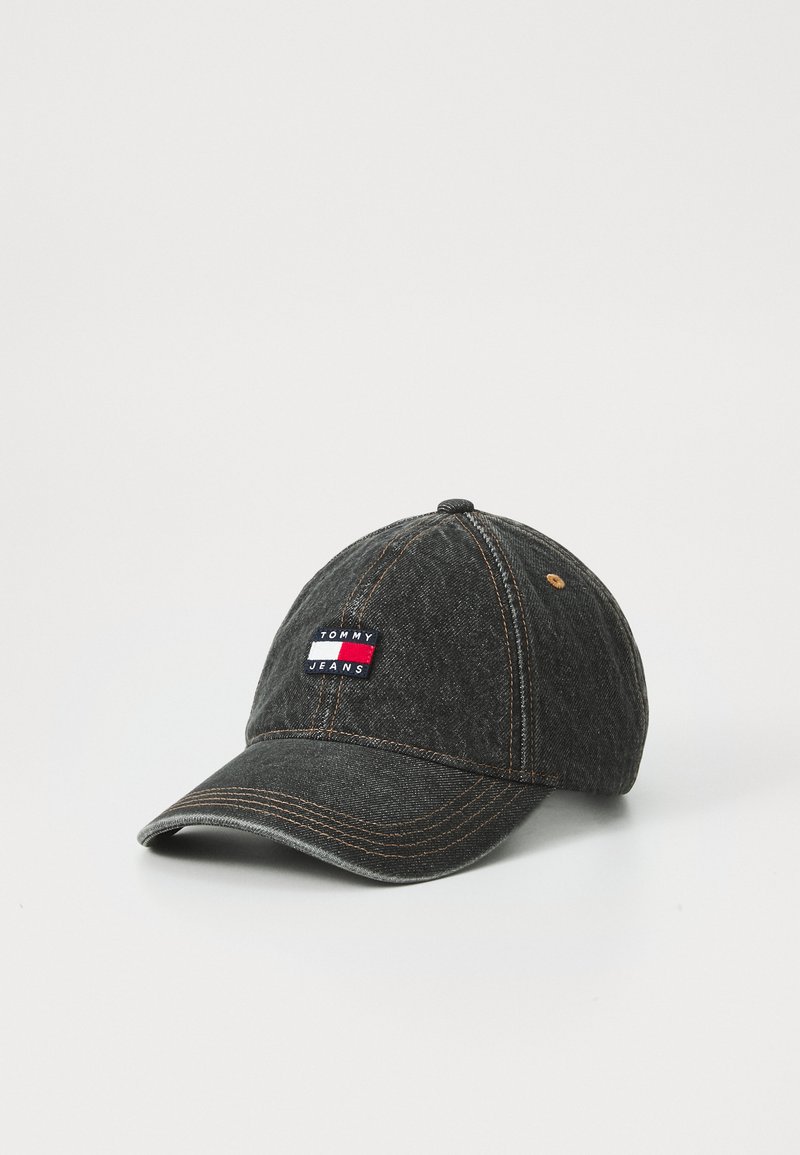 Gray denim cap with a curved brim, orange stitching, and a rectangular logo patch featuring the text "TOMMY JEANS" in red, white, and blue.