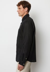 Zwarte, lange mouwen shirt gemaakt van een textuurstof. Heeft een knoopsluiting, kraag en een borstzak. Tailored fit.