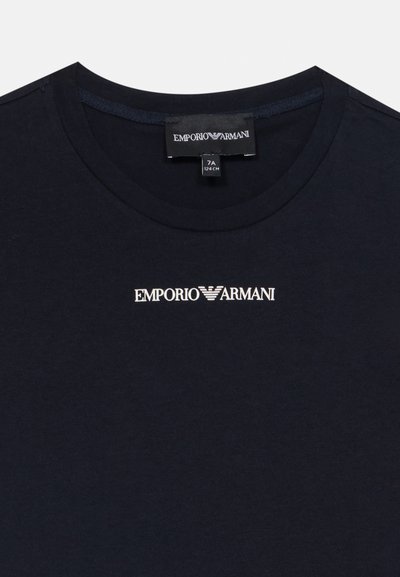 Navy zila kokvilnas T-krekls ar apaļu kaklu un izšūtu Emporio Armani logo baltā krāsā uz krūts. Mīksta tekstūra, standarta piegriezums.