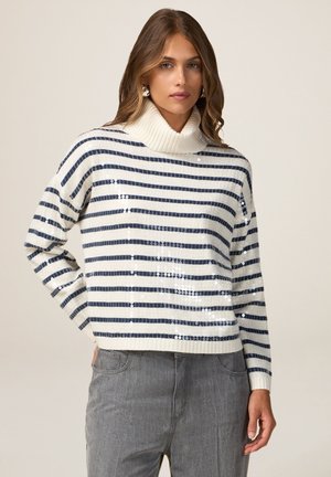 Pull rayé en crème et marine, avec un col roulé, une texture côtelée et des détails en sequins à l'avant. Coupe crop, manches longues.
