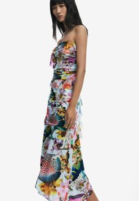 Strapless floral maxi dress with ruffles, featuring a mix of vibrant colors, sheer fabric, and a layered skirt design.