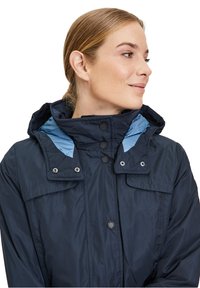 Marineblaue wasserdichte Jacke mit einem hellblauen Innenfutter der Kapuze, sechs vorderen Knöpfen, zwei Brusttaschen und einem hohen Kragen für zusätzliche Wärme.