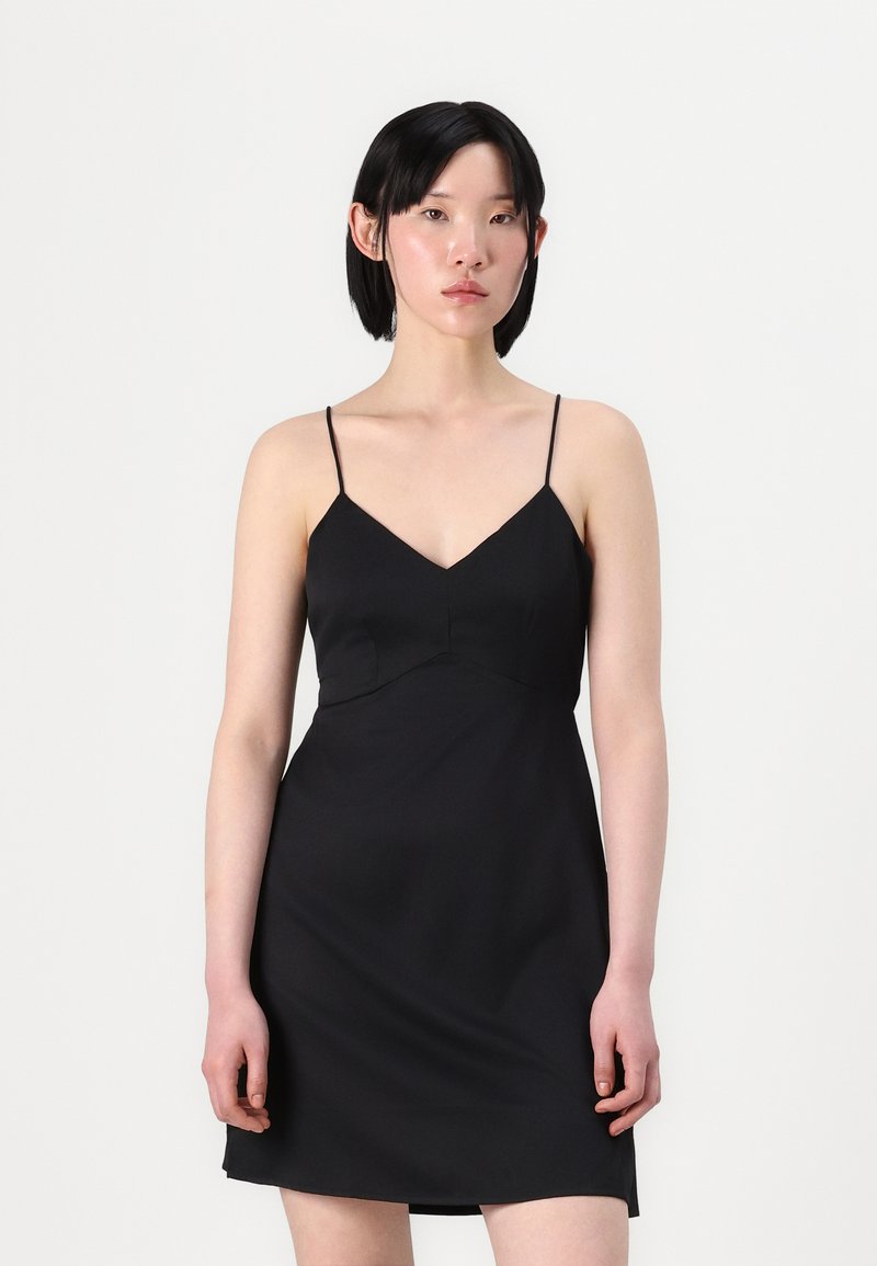 Vestido preto justo com alças finas, decote em V, corpete justo e saia fluida. Textura suave, design minimalista, comprimento acima do joelho.