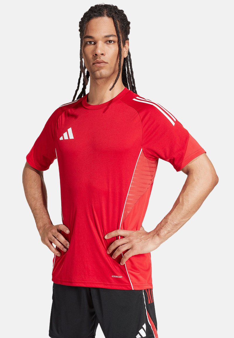 T-shirt de sport rouge avec col rond, manches courtes et bandes blanches. Fabriqué en tissu qui évacue l'humidité avec des panneaux latéraux texturés.