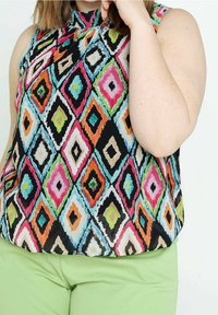 Ärmless blus med ett flerfärgat diamantmönster på en svart bakgrund, hög halsringning och lätt, slät tyg.