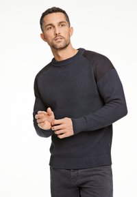 Dunkelblauer gerippter Pullover mit Schulterakzenten aus schwarzem Wildleder, Rundhals, langen Ärmeln und engen Bündchen. Lässiges Design mit strukturiertem Finish.