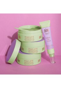 Grüne Gläser mit der Aufschrift "Dream-yEYE" und lila Deckeln enthalten Augenkissen; neben ihnen liegt eine lavendelfarbene Tube mit der Aufschrift "Retinol Augencreme".