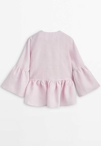 Blouse rose à manches longues en tissu léger, avec des manches évasées et un ourlet à volants, un col rond et sans fermetures visibles.