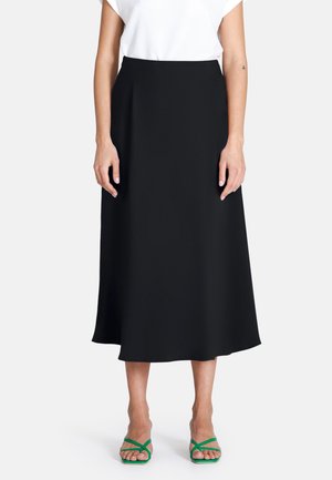 Zwarte midi-rok met een gladde textuur en een uitlopende stijl. Gekozen in combinatie met een witte top en groene sandalen met bandjes. Eenvoudige en veelzijdige stijl.