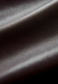 Sötétbarna, texturált bőr szövet, finom fényű, amely finom szemcsés mintázattal és sima felülettel rendelkezik.