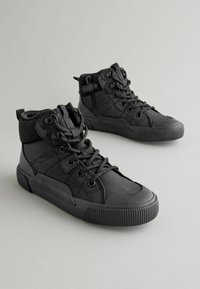 Schwarze High-Top-Sneaker mit Obermaterial aus strukturiertem Gewebe, Gummisohle, verstärkter Zehenkappe und Metallösen. Mit seitlichem Reißverschluss für ein einfaches An- und Ausziehen.
