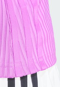 Roze geribbelde top met verticale strepen, gestructureerde stof en een getailleerd ontwerp, met een schone zoom en contrasterende witte stof eronder.
