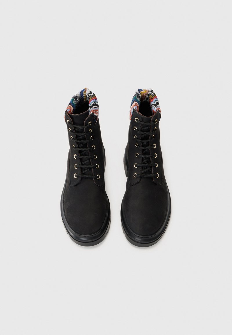 Svarta snörkängor med en slät yta, med en färgglad mönstrad kant och gyllene öglor för snörena. Gummisula för bra fäste.