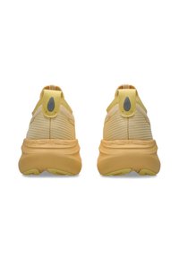 Baskets de sport jaunes avec une tige en maille texturée, une semelle extérieure incurvée et deux tirants. Logo ASICS sur le talon.