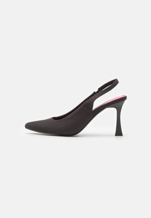 Zwarte high heel slingback met spitse neus, slanke gebogen hak en roze binnenzool zichtbaar aan de achterkant.