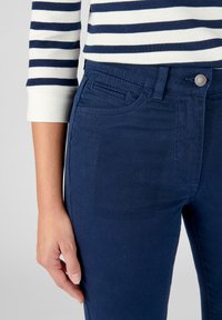 Donkerblauwe jeans van een rekbare stof, met een klassiek vijf-pocketdesign en een zichtbare sluiting met een knop en rits aan de voorkant.