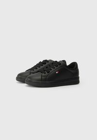 Baskets en cuir noir avec une texture lisse, bout rond et design à lacets. Comprend un petit logo tricolore sur le côté et une semelle en caoutchouc.