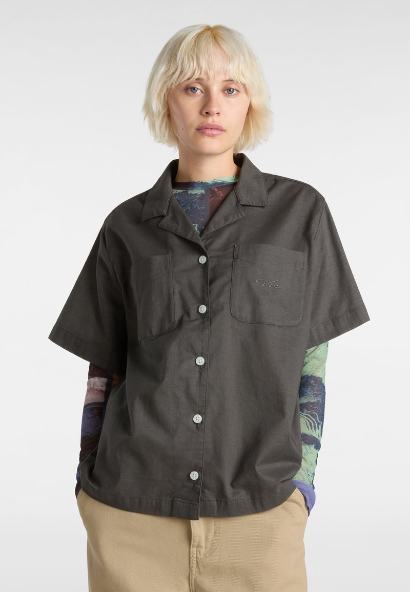 Chemise à manches courtes, gris foncé, avec un col, deux poches poitrine, des boutons blancs et un tissu texturé.