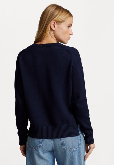 Donkerblauwe gebreide pullover met geribde manchetten en zoom, ronde halslijn en gestructureerde stof. De achterkant heeft raglanmouwen en een relaxed fit.