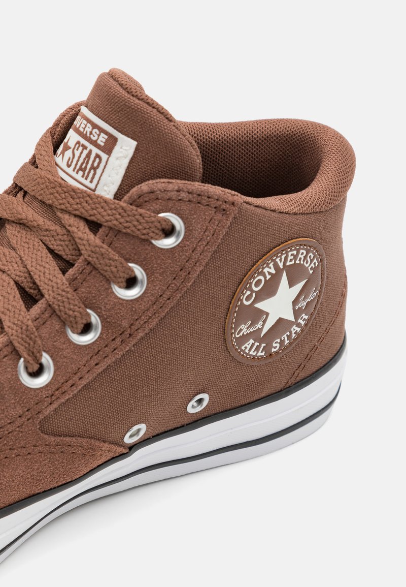 Sneaker montante en toile marron avec semelle en caoutchouc, bout rond, surface texturée et coutures blanches. Présente un patch logo Converse sur le côté.