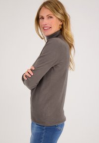 Grijze sweater met een hoge kraag, lange mouwen en een slim-fit ontwerp. Gemaakt van zacht materiaal, voorzien van een geribde zoom en subtiele structuur.