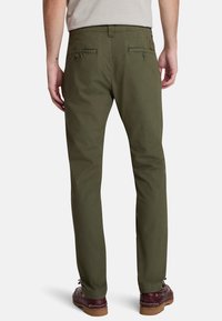 Pantaloni verde oliva con taglio dritto, realizzati in tessuto leggero, dotati di due tasche posteriori e dettagli di cucitura sottili.