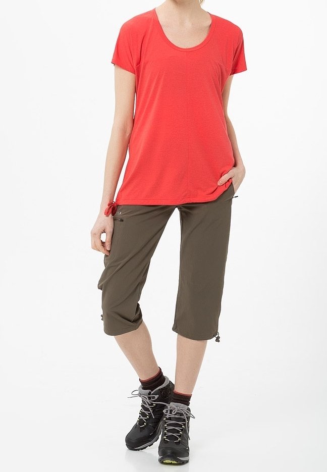 Camiseta roja de manga corta con escote redondo, combinada con pantalones verde oliva hasta la rodilla que cuentan con cordones y cremalleras. Botas de senderismo negras.