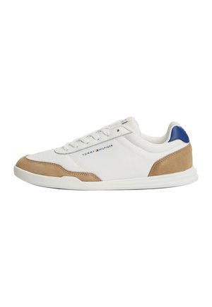 Hvid lavtop sneakers med beige ruskind detaljer, blå hældetalje og "Tommy Hilfiger" logo på siden, snørelukning og gummisål.