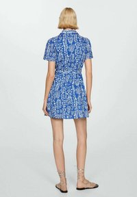 Abito blu a maniche corte con stampa floreale bianca, vita aderente e gonna svasata. Presenta un colletto e una lunghezza al ginocchio.
