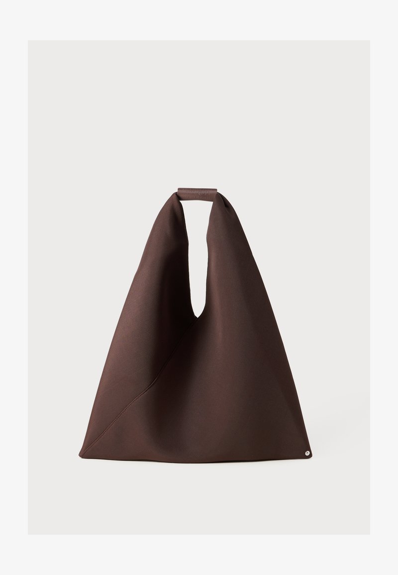 Brūns auduma iepirkumu soma ar unikālu formu, kurai ir plaša atvere, teksturēta virsma un mazs apļa akcents apakšā.