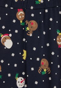 Mornarska tkanina z belimi snežinkami in pisanimi prazničnimi vzorci, vključno z jeleni, moški iz ingverjevega kruha in snežaki.