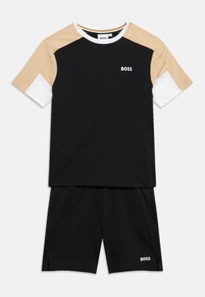 Maglietta nera a maniche corte con maniche beige e bianche, abbinata a pantaloncini neri, entrambi con il logo bianco "BOSS".