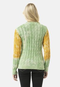 Gebreide trui met een kabelpatroon; groene body en geel-oranje mouwen; geribbelde kraag en zoom; textiel, zachte stof.