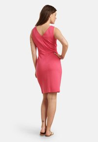Roze aansluitende jurk met een V-rug ontwerp, gemaakt van een gladde stof. Knie-lange zoom en eenvoudig, zonder versieringen of patronen.