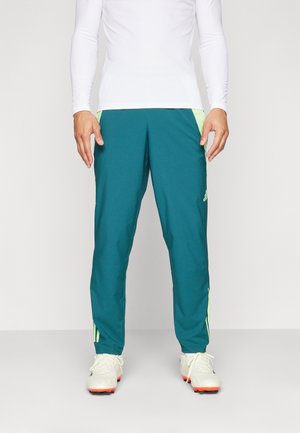 Pantalons de sport teal avec des accents vert clair, fabriqués dans un tissu lisse. Comprend une taille élastique et des bandes latérales pour la respirabilité.