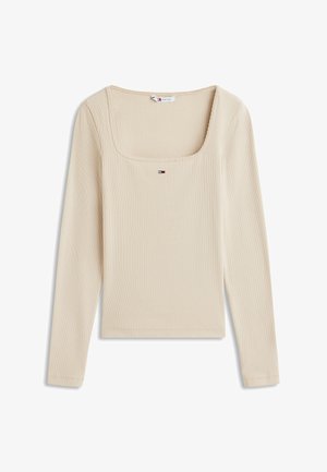 Beżowa bluzka z długim rękawem, prążkowana, z kwadratowym dekoltem i małym logo Tommy Jeans umiejscowionym na środku poniżej kołnierza.