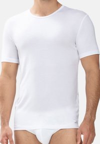 T-shirt blanc à manches courtes en tissu doux, avec un col ras du cou classique et une coupe slim. Pas de logos ni de motifs visibles.
