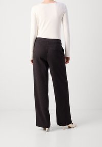 Zwarte pinstripe wijde broek met een gestructureerde pasvorm, met een zachte textuur en een elastische tailleband, gecombineerd met een strakke witte top.