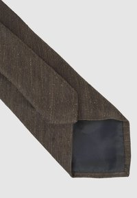 Corbata de lana marrón con un patrón texturizado, forma afilada y un forro de tela oscura y suave en el extremo ancho.