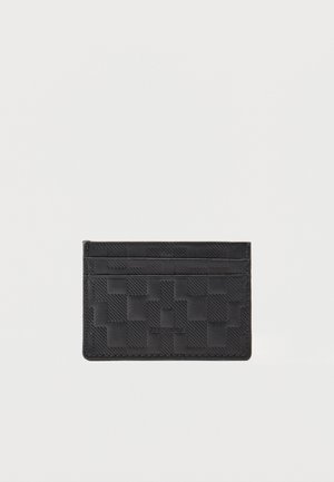 Čierny kožený držiak na karty s vyrazeným károvaným vzorom a tromi priehradkami na karty na jednoduchom bielom pozadí.