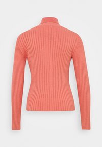 Pull côtelé corail avec un col montant et des manches longues. Le tissu est texturé, avec des rayures verticales qui mettent en valeur la silhouette ajustée.