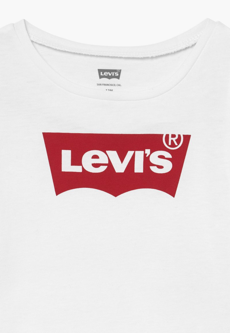 Camiseta de algodón blanca con un gran logo rojo de Levi's con un borde inferior curvado, centrado en la zona del pecho. Cuello redondo.