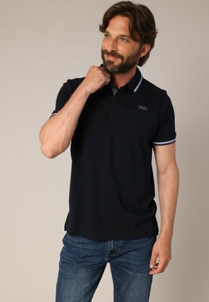 Zwarte poloshirt met een kraag, voorzien van drie knopen en witte accenten op de mouwen. Zacht materiaal en een slank pasvorm ontwerp.