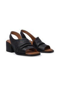 Zwarte leren slingbackschoenen met een geknoopt design, open teen en blokhak. Bruine binnenvoering en textuur aan de buitenkant.
