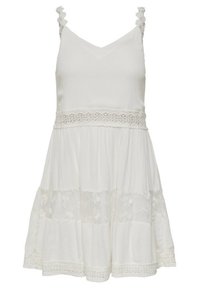 Vit ärmlös klänning med V-ringning, spetsdetaljer vid midjan, volangaxelband och flera lager av tyg med spetsaccenter.