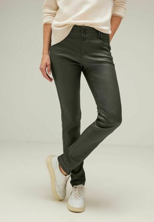 Olive green fitted pants with a smooth texture, featuring a two-button closure, five pockets, and subtle stitching details, paired with white sneakers.